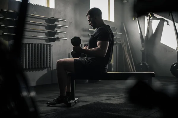 Serious Sportsman Sit on Bench and Lift Dumbbells . — Stock Photo, Image