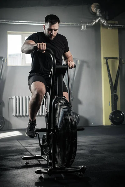 L'homme athlétique utilise le vélo d'exercice au gymnase . — Photo