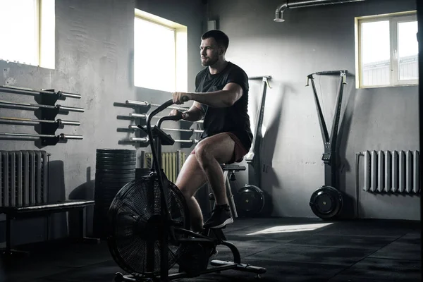 Serious Handsome Male Make Exercises on Stationary Bike . — Stock Photo, Image