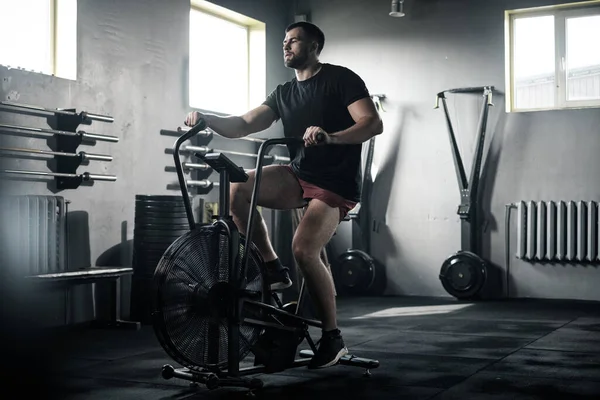 Lo sportivo allena i muscoli delle gambe su una bici stazionaria . — Foto Stock