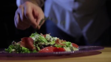 Şef düzeltiyor ve müşterilere hizmet öncesi yemek süsleyen