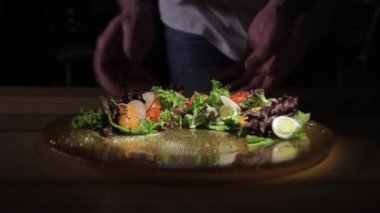 Şef düzeltiyor ve müşterilere hizmet öncesi yemek süsleyen