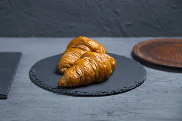 classic French croissants, baked goods on a gray background lies on a crafting dish
