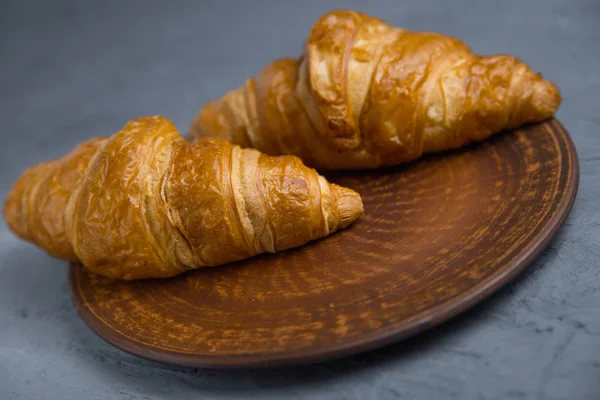classic French croissants, baked goods on a gray background lies on a crafting dish