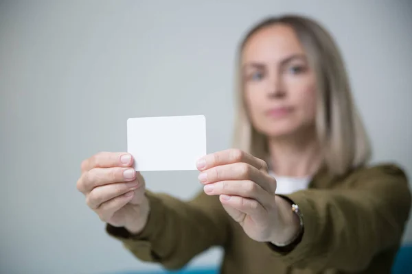 A young woman holds a business card in her hands.