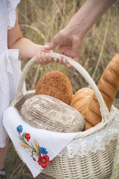 Hasır sepetin içindeki bir açıklıkta ekmek ekmeği işlemeli bir havlu yatıyor.