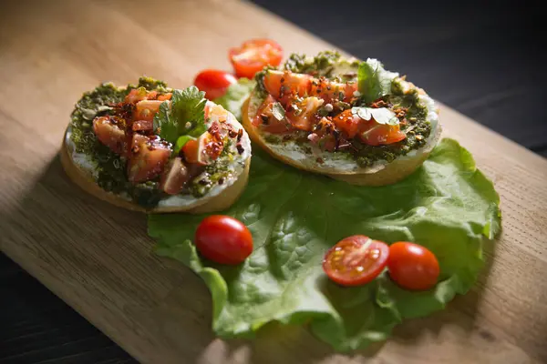 Tahta bir masanın üzerinde domatesli ve marullu sandviçler yatıyor.