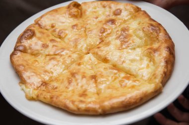 Peynirli khachapuri yuvarlak tabakta yatıyor.
