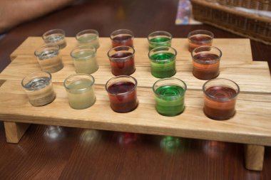 Çeşitli içkilerle dolu bardaklar ahşap tezgahta.