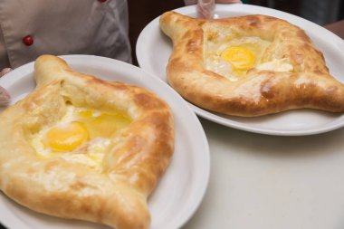 Çiğ yumurtayla iştah açıcı khachapuri tabakta yatıyor.