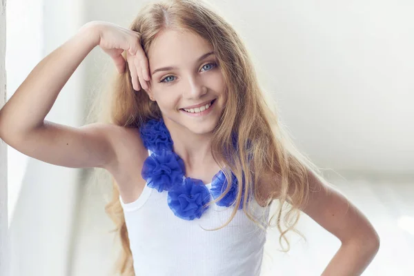 Egy boldog kis lány modell bájos mosollyal pózol egy stúdió-portré. — Stock Fotó