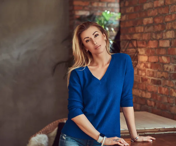 Módní blondýna žena vystupují proti cihlové zdi ve studiu se interiér podkroví. — Stock fotografie