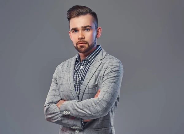 Handsome bearded man with hairstyle in an elegant gray jacket, posing with crossed arms in a studio, looking at a camera. — Stock Photo, Image