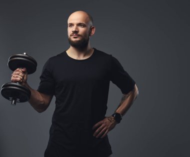 Yakın çekim portre siyah t-shirt bir stüdyoda dumbbell poz, yakışıklı bir sakallı atlet.