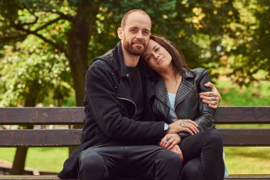 Bir parkta bir bankta oturmuş çekici modern Çift.