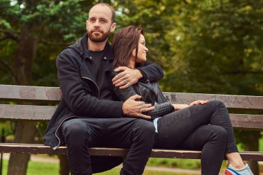 Bir parkta bir bankta oturmuş çekici modern Çift.