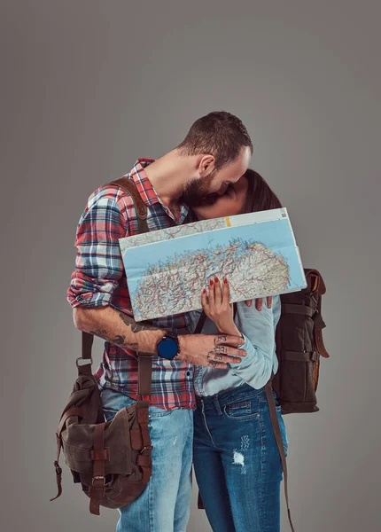 Aantrekkelijke aantal toeristen zoenen terwijl die betrekking hebben op hun gezicht met een kaart, knuffelen in een studio. — Stockfoto