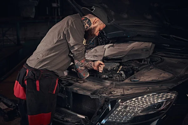 Mécanicien automobile vérifie le moteur de la voiture lors de la réparation dans un garage . — Photo