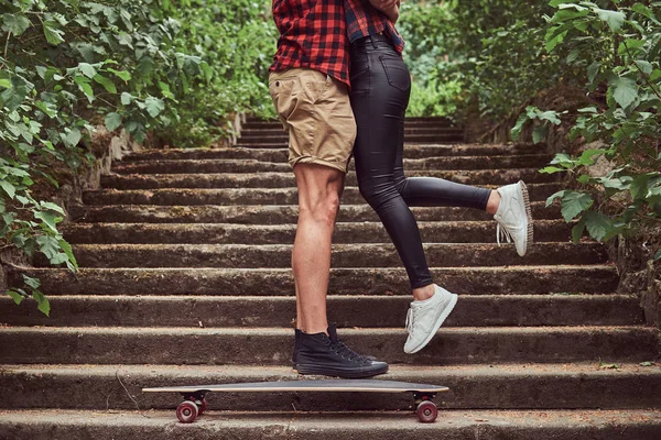 Beskuren bild av unga hipster par, krama stående på stegen i en park. — Stockfoto