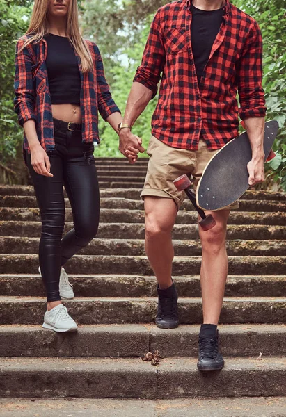 Junges Hipster-Paar, geht in einem Park, hält sich an den Händen, steigt die Treppe hinunter. — Stockfoto