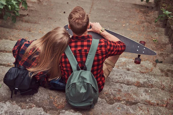 Baksidan på en ung hipster par, sitter på stegen i en park. — Stockfoto