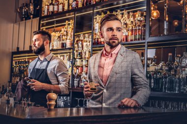 Bir bardak viski bar counter arka plan bir şık elbiseli şık yakışıklı adam tutar.