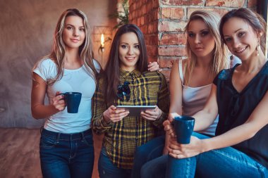 İn kadın arkadaş grubu ile rahat kıyafetler tartışırken süre seyir bir şey bir odada dijital tablet ile bir çatı katı iç.