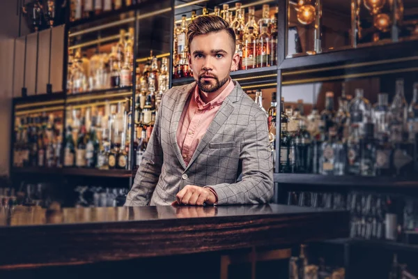 Stylish handsome man in an elegant suit standing at bar counter background.