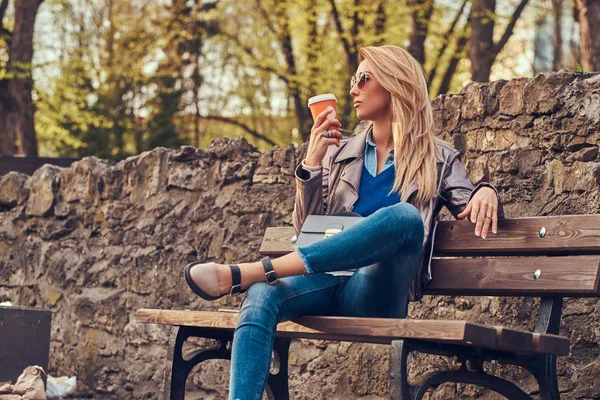 Fashionable Blonde Female Relaxes Outdoor Drinking Takeaway Coffee While Sitting — Stock Photo, Image