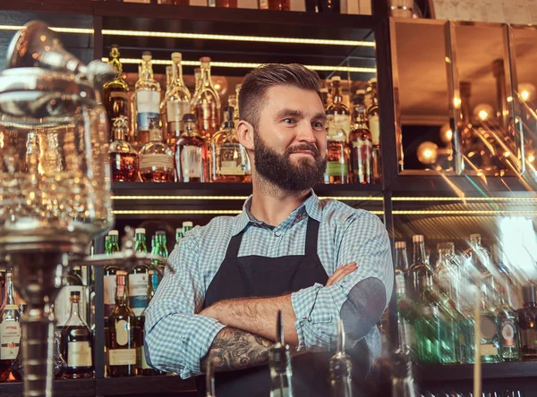 时髦的野蛮酒保在衬衫和围裙站立与交叉的胳膊在酒吧柜台背景 — 图库照片