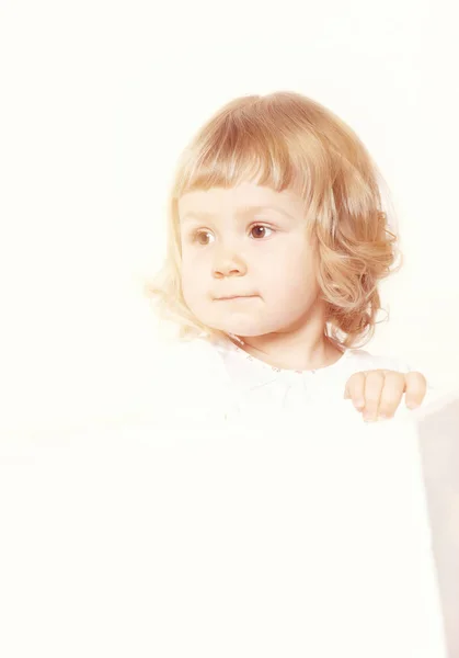 Porträtt av en söt liten flicka i en vit klänning på vit bakgrund — Stockfoto