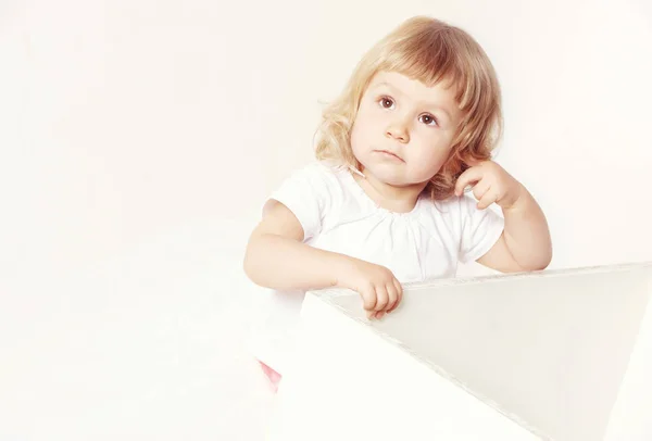 Retrato de uma menina bonito pensativo em um vestido branco no fundo branco . — Fotografia de Stock