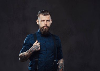Yakışıklı bir eski moda hippi bir stüdyoda poz mavi bir gömlek ve pantolon askısı, portresi.