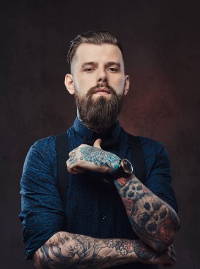 Yakışıklı bir eski moda hippi bir stüdyoda poz mavi bir gömlek ve pantolon askısı, portresi.