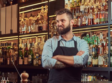 Bir gömlek ve önlük ayakta bar counter arka plan çapraz kollu şık acımasız barmen.