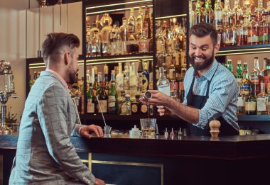Neşeli şık acımasız barmen bir gömlek ve önlük, müşteri sayacı arka plan bar hizmet vermektedir..