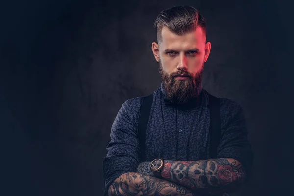 Retrato de un guapo hipster a la antigua con una camisa azul y tirantes, de pie con los brazos cruzados en un estudio . —  Fotos de Stock