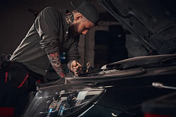 Auto mechanik sprawdza silnik samochodu podczas napraw w garażu. — Zdjęcie stockowe