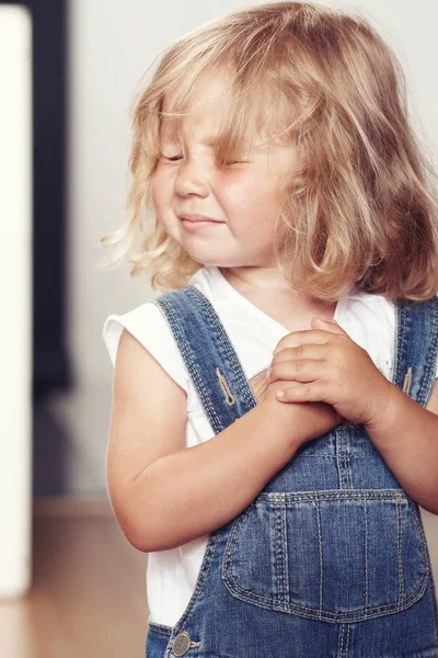 Portrait d'une petite fille bouleversée en salopette denim, debout en studio . — Photo