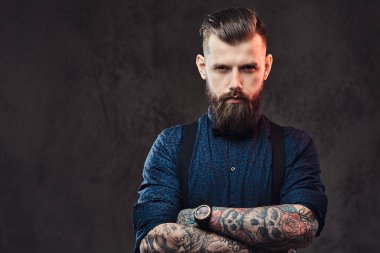 Mavi bir gömlek ve bir stüdyo çapraz kollarında ile ayakta pantolon askısı, yakışıklı bir eski moda hipster portresi.