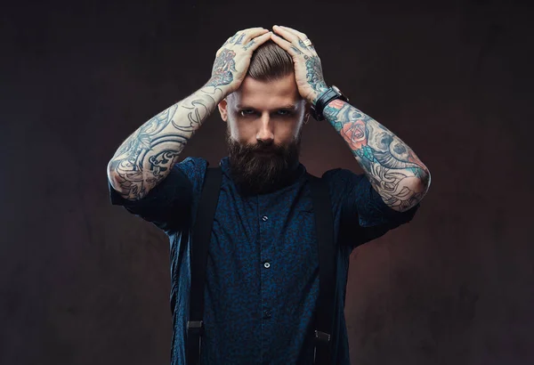 Desesperado tipo hipster a la antigua en una camisa azul y tirantes de pie en un estudio . — Foto de Stock