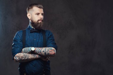 Mavi bir gömlek ve bir stüdyo çapraz kollarında ile ayakta pantolon askısı, yakışıklı bir eski moda hipster portresi.