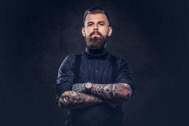 Mavi bir gömlek ve bir stüdyo çapraz kollarında ile ayakta pantolon askısı, yakışıklı bir eski moda hipster portresi.