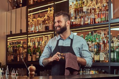Neşeli şık acımasız barmen bir bezle bar counter arka plan cam temizlik.