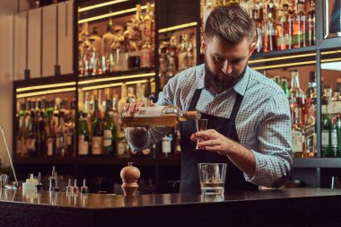 Bir gömlek ve önlük şık acımasız barmen, bir kokteyl bar counter arka plan yapar.