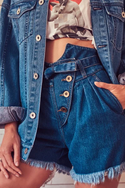 Cropped image of a sexy slim young girl wearing short denim shorts and jeans jacket.