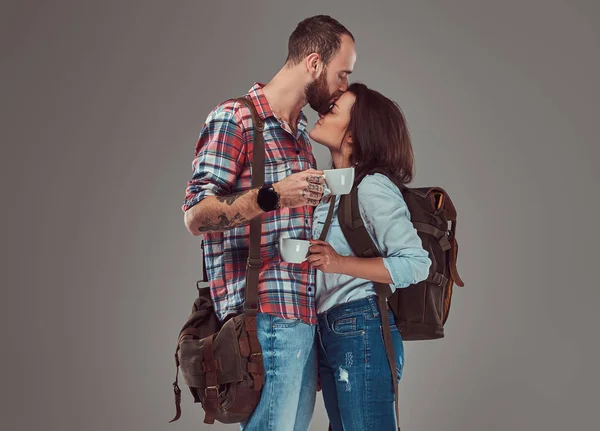 Feliz pareja de turistas besándose mientras sostiene tazas de un café . — Foto de Stock