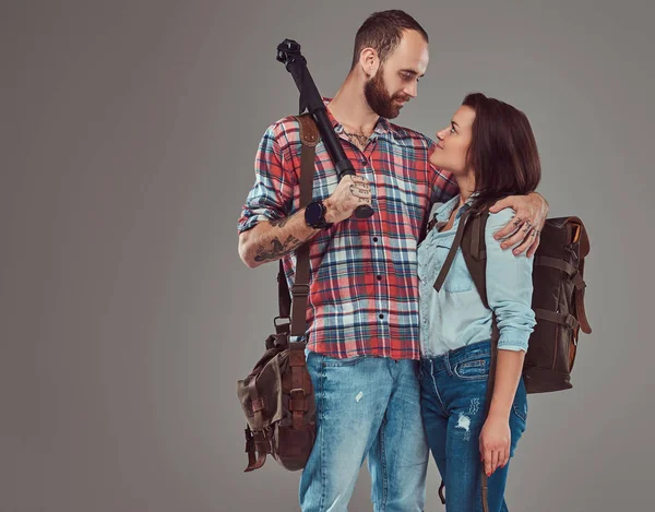 Retrato de estudio de turistas masculinos y femeninos con mochila y trípode, abrazándose en un estudio . — Foto de Stock