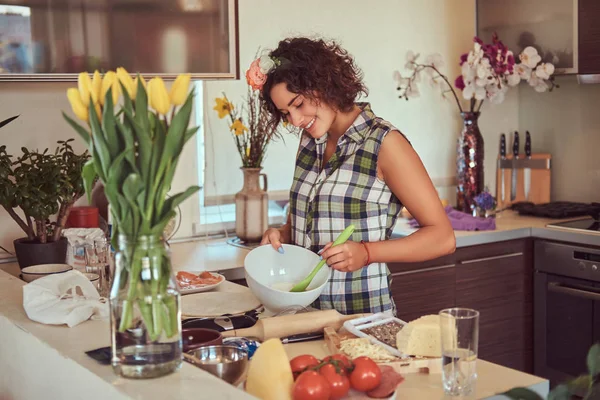 Charmig lockigt spansktalande tjej matlagning i hennes kök. — Stockfoto