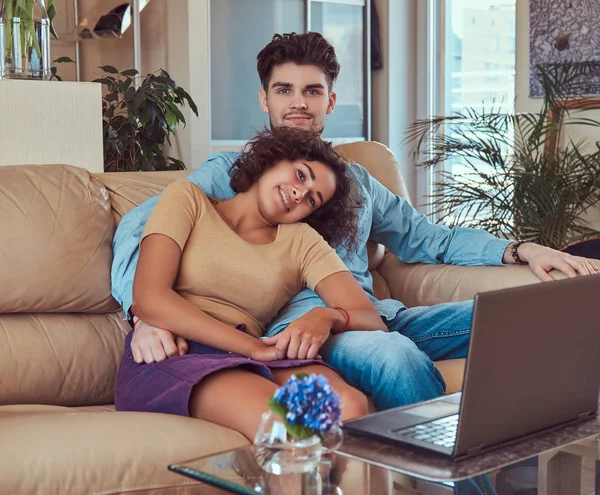 Ευτυχισμένο ζευγάρι ελκυστική κατά τη διάρκεια ενός Σαββατοκύριακου, βλέποντας την ταινία για το φορητό υπολογιστή που κάθεται στον καναπέ στο σπίτι. — Φωτογραφία Αρχείου